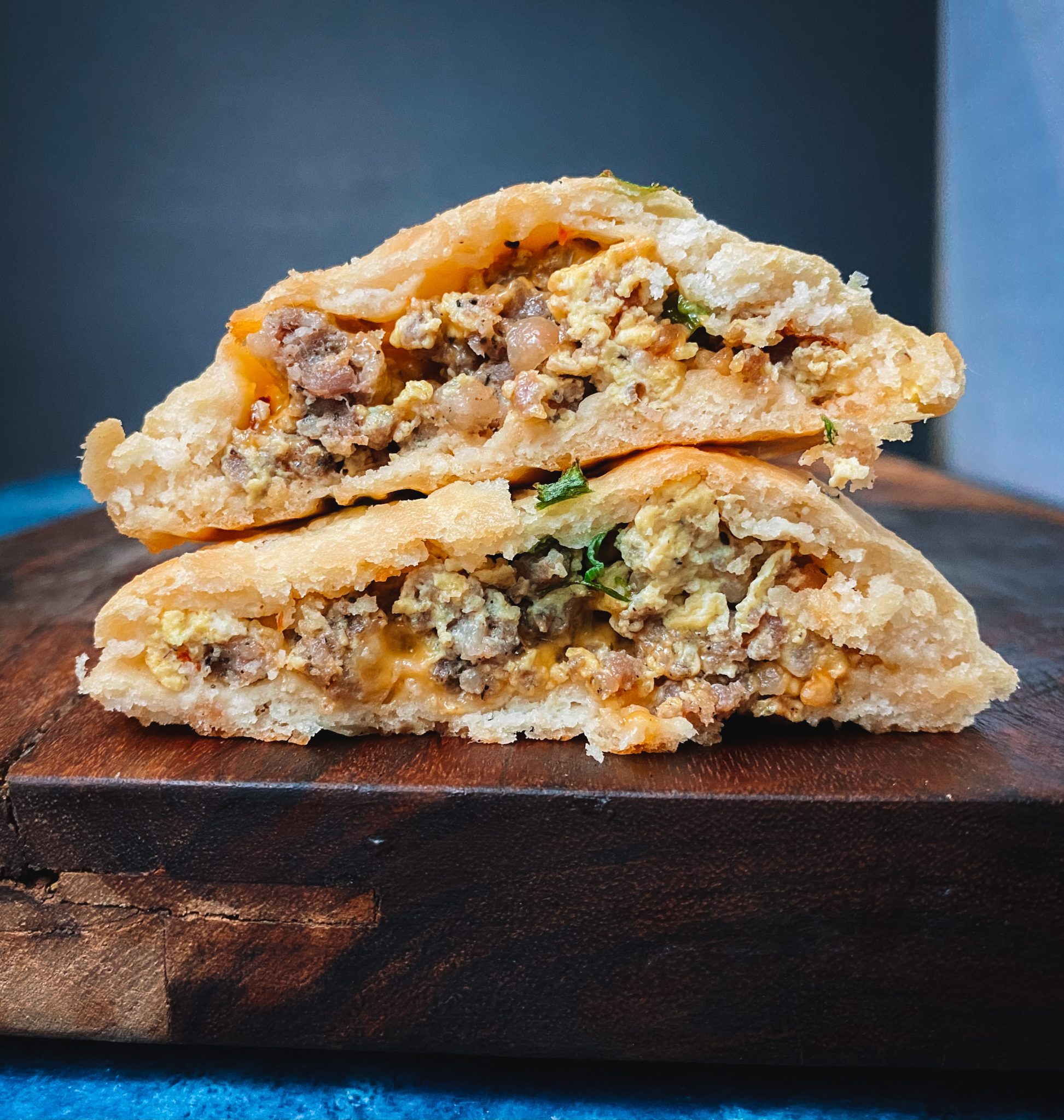 Keto stuffed breakfast biscuit, cut in half and stacked on top of each other on a brown wood table