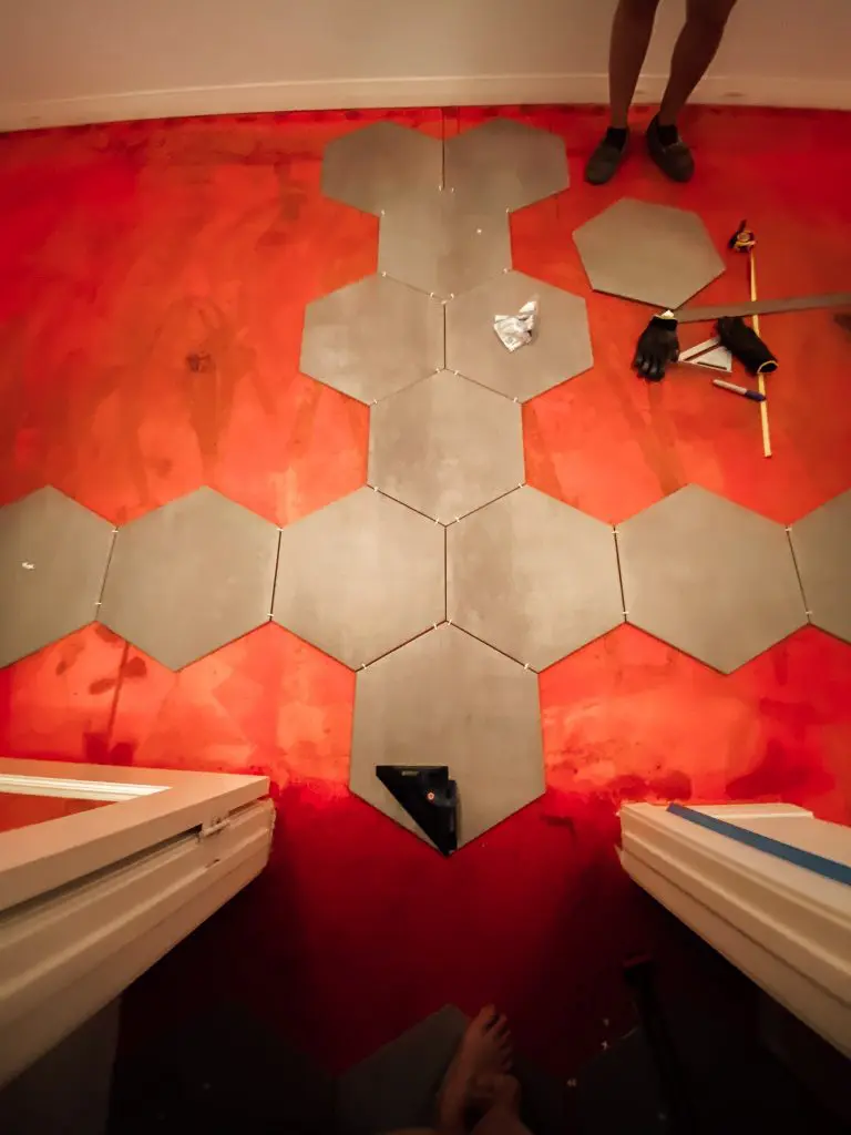 laying out tile to determine a pattern with red waterproofing membrane