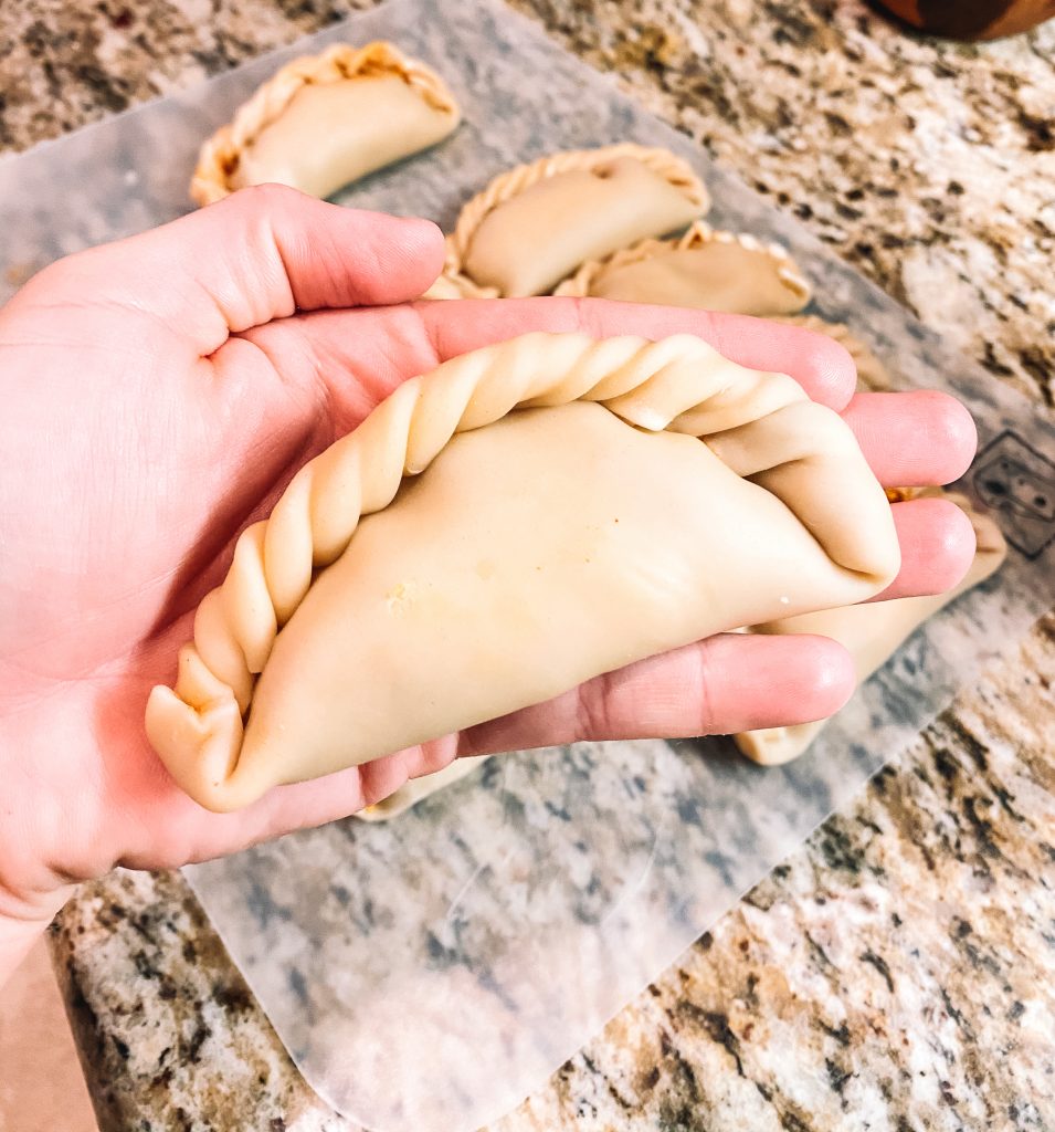 sealed and crimped chili cheese empanada in hand 