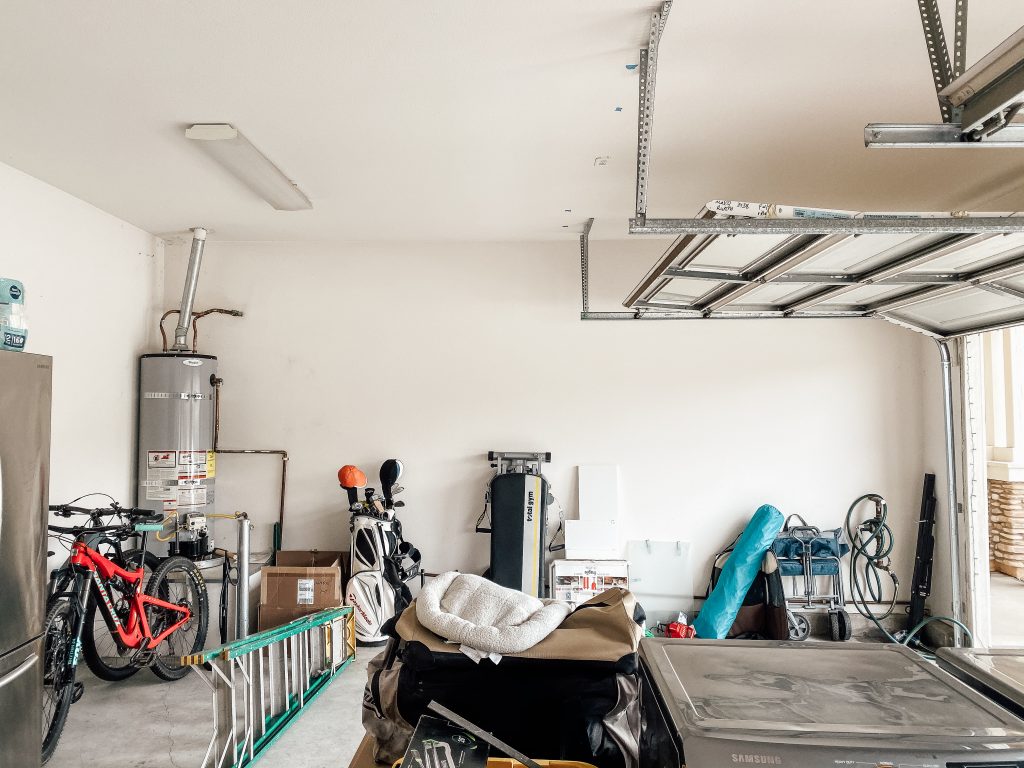 garage with golf bags, bikes, ladder and other stuff strewn about